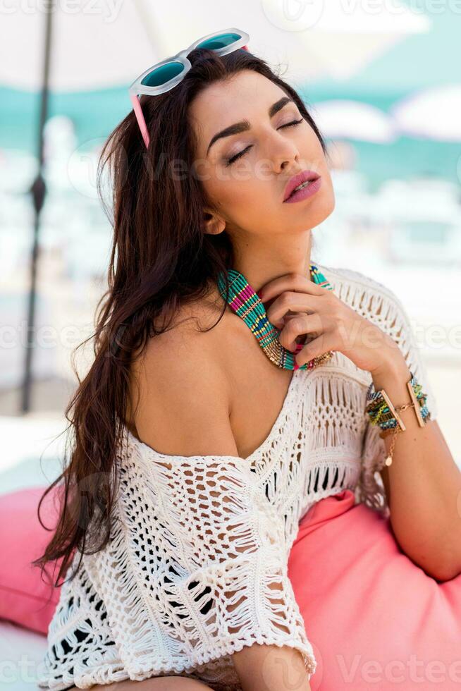 Summer portrait of beautiful brunette woman chilling  in the beach club. Tropical acsessories. photo
