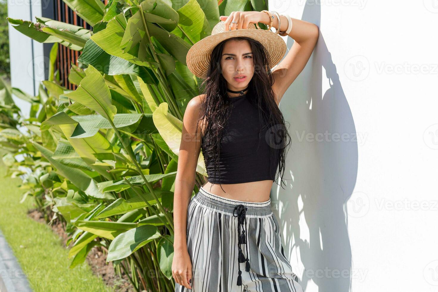 Sexy brunette with tan body in straw hat posing outdoor. Summer fashion trends. Tropical mood. photo