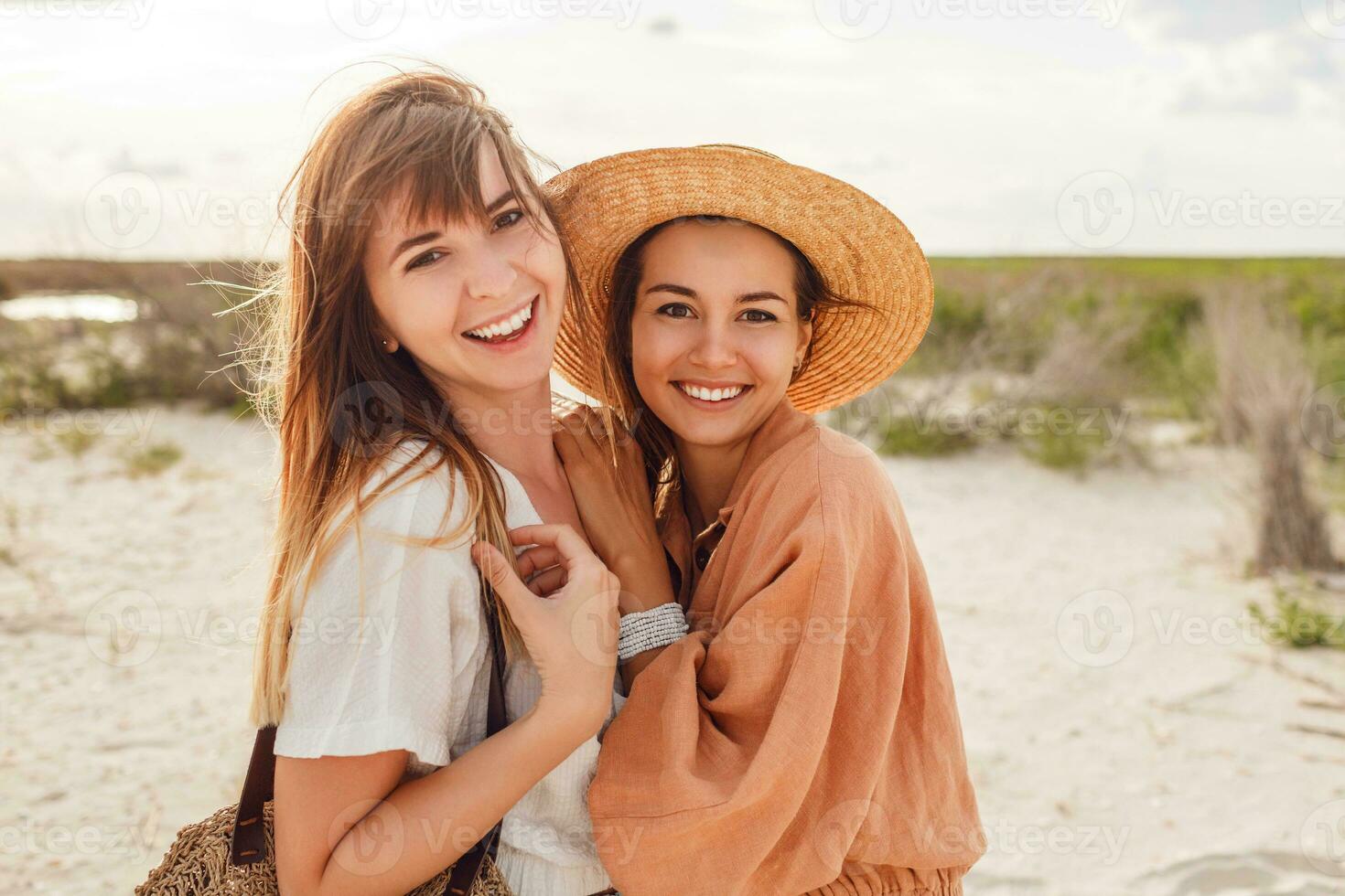 a woman in an orange dress and hat on the beach photo