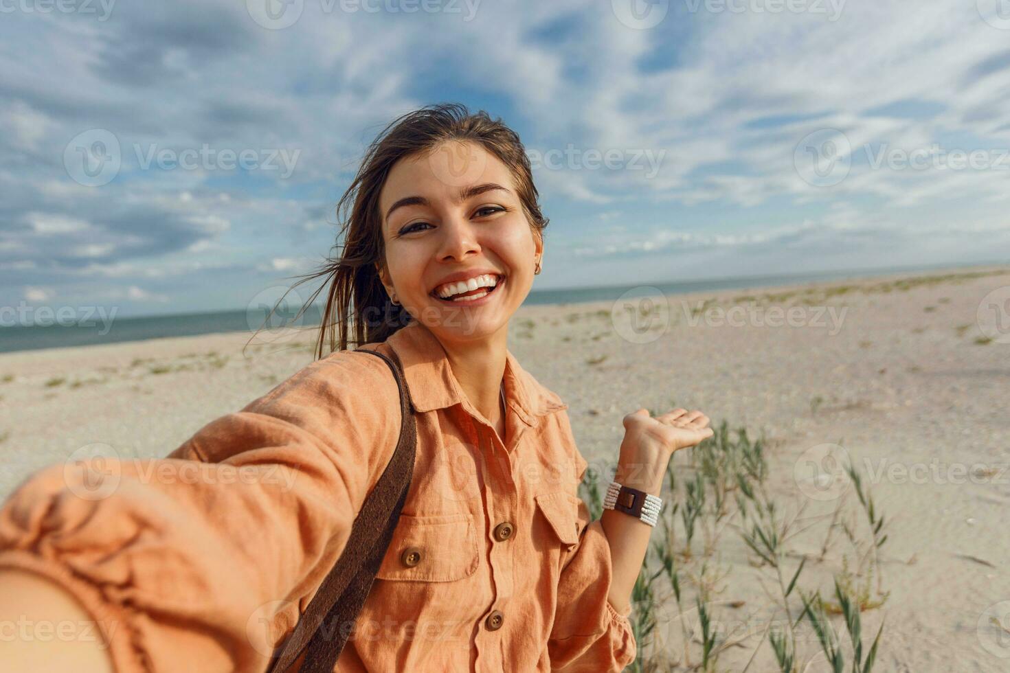 un mujer en un naranja vestir y sombrero en el playa foto