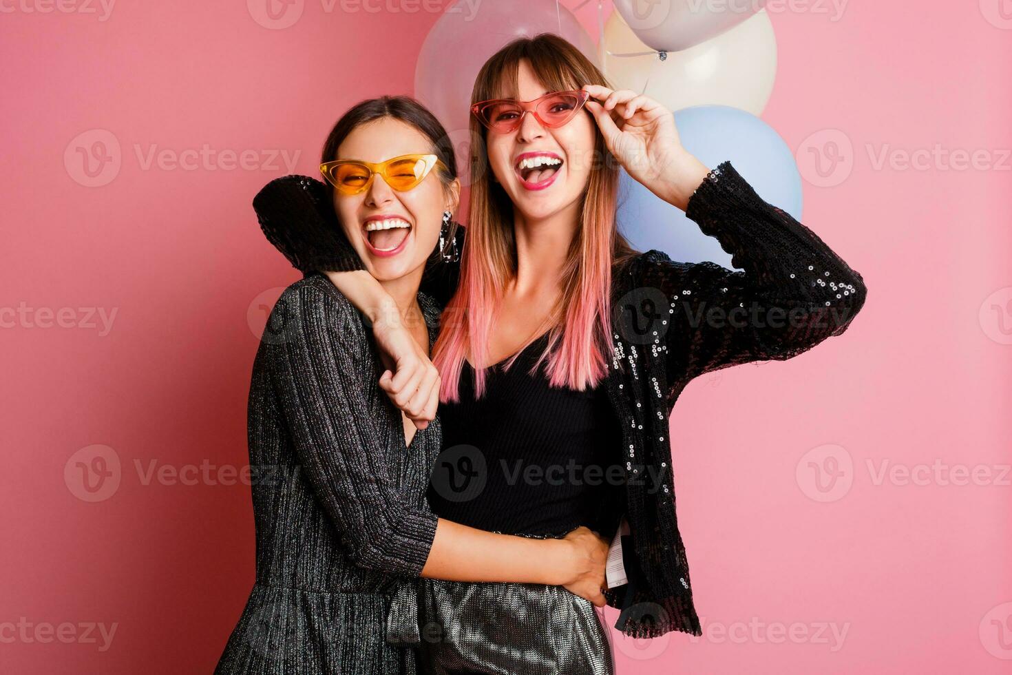 dos mujer , mejor amigos celebrando gallina fiesta, posando con nupcial foto accesorios en rosado antecedentes.