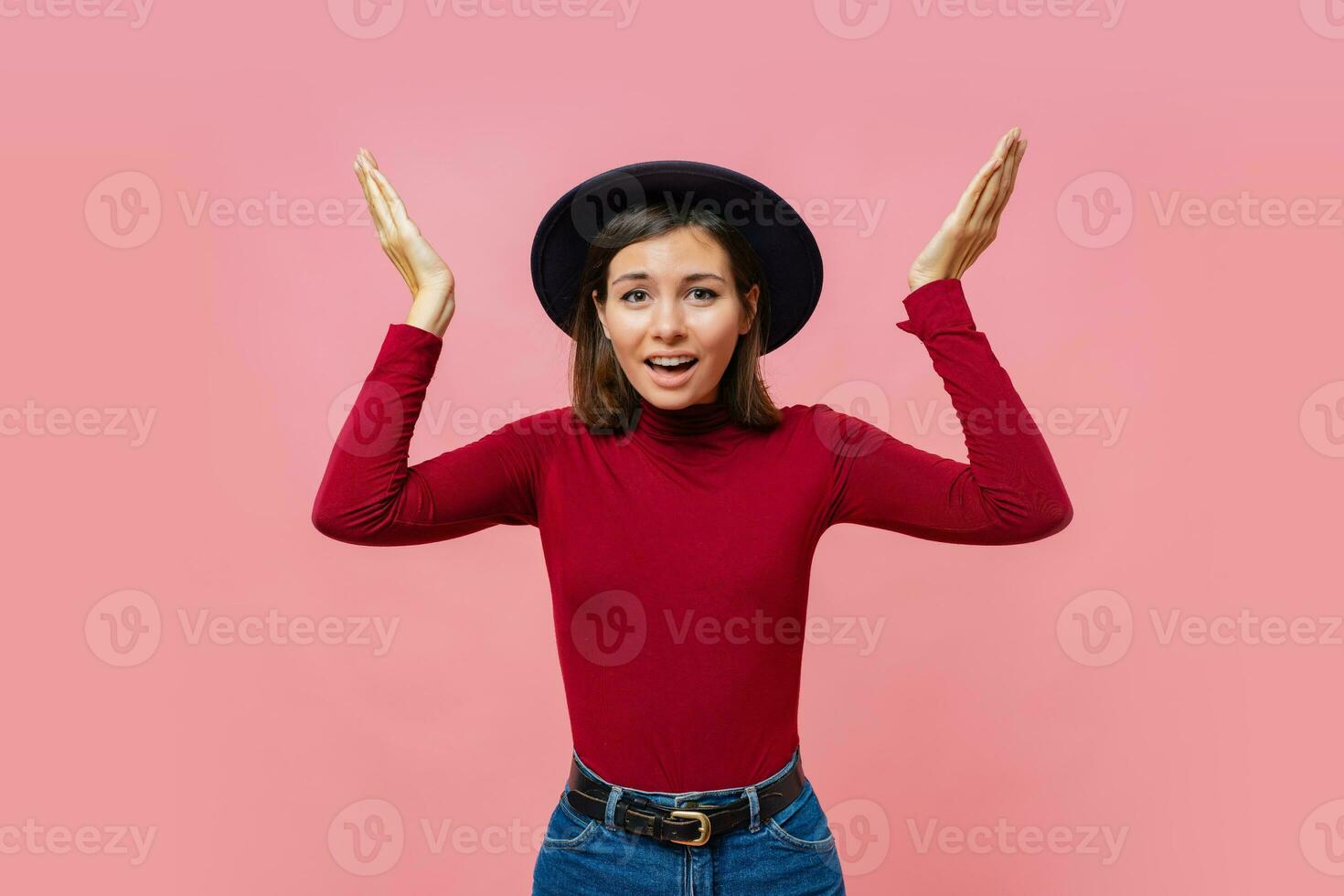 Puzzled  cute  female  spreads hands with doubt, dressed in  red  jumper, isolated over  pink background, blank copy space. Woman faces dilemma, being unsure photo