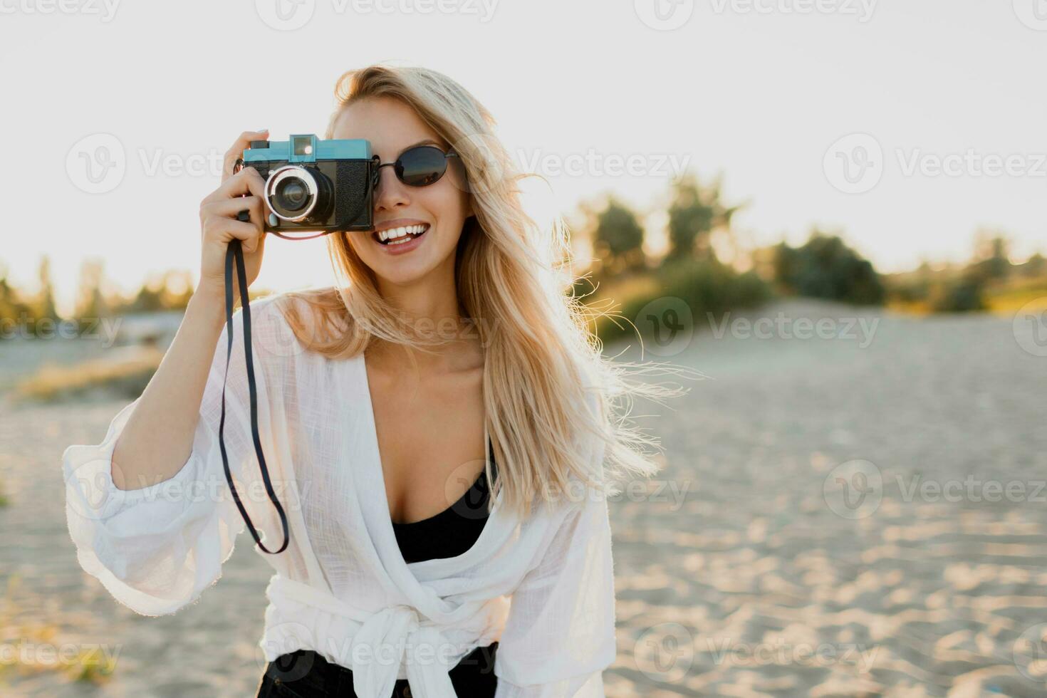 Stylish girl with retro camera on sunny beach. Summer vacation. Freedom and travel concept. photo