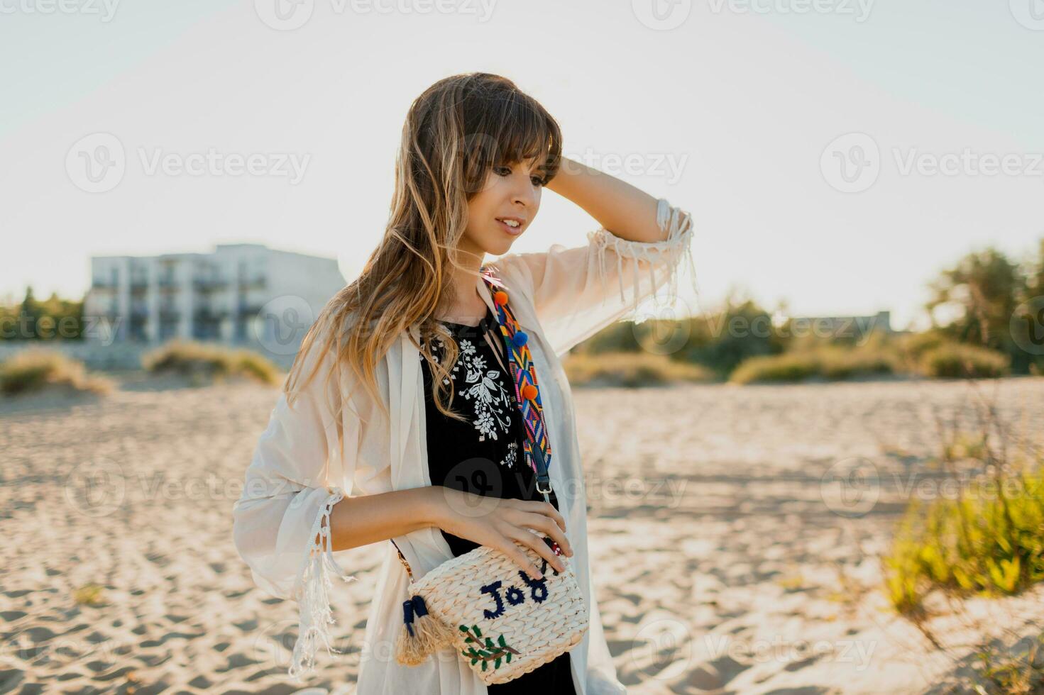 Romantic girl with long hair walking on the beach.   Bohemian style, straw bag , bright make up. photo