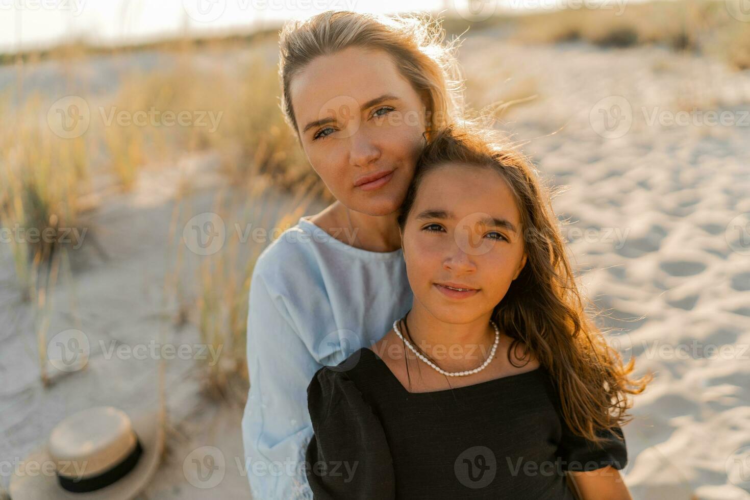 al aire libre retrato de hermosa familia. madre y hija posando en el playa. calentar puesta de sol colores. foto