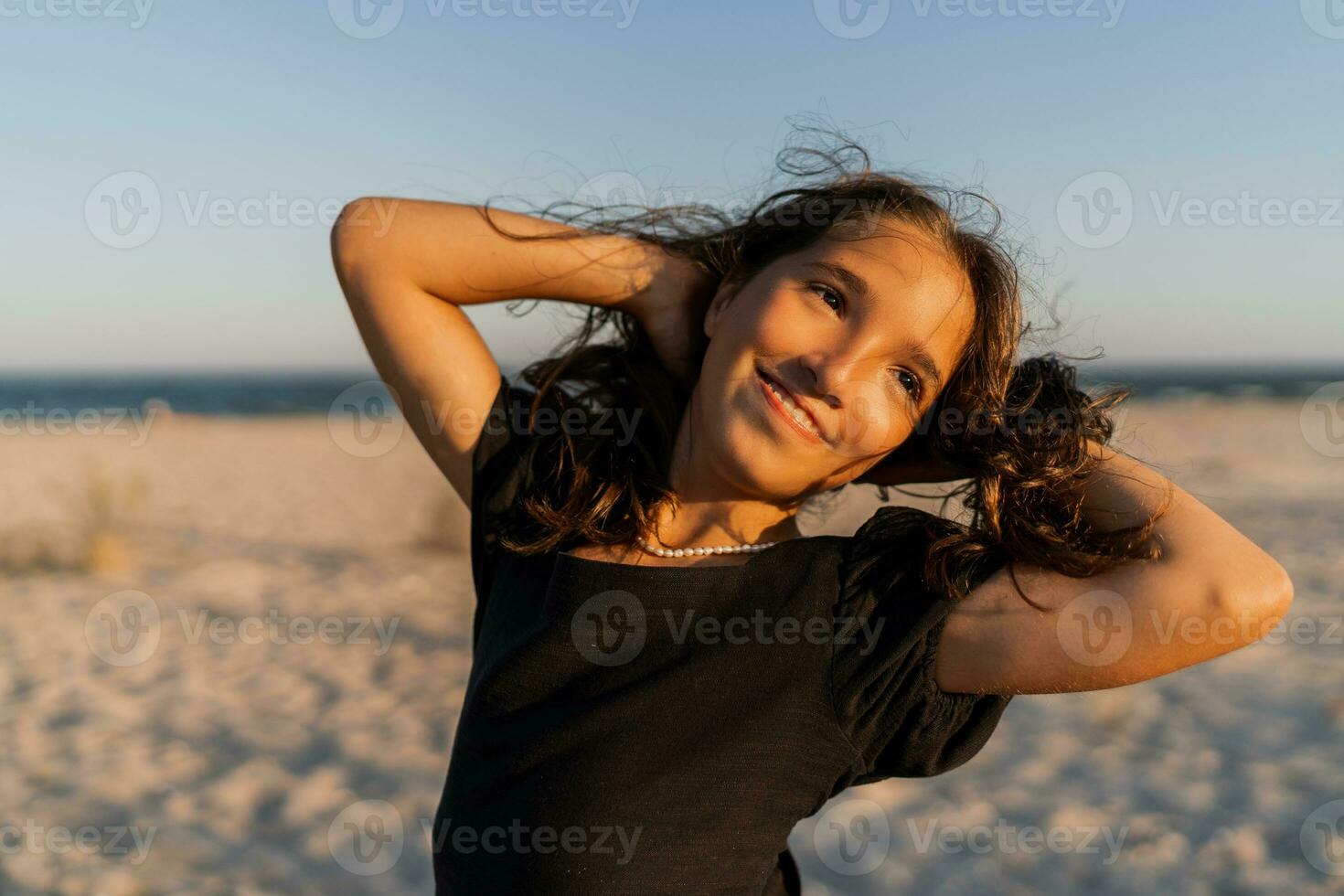 hermosa morena niño niña posando om el playa. puesta de sol calentar colores. foto