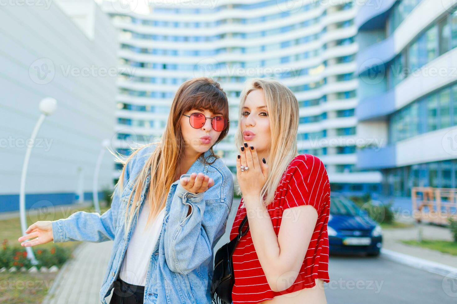 cerca arriba verano retrato de dos mujer riendo y náuseas al aire libre en el calle. urbano antecedentes foto