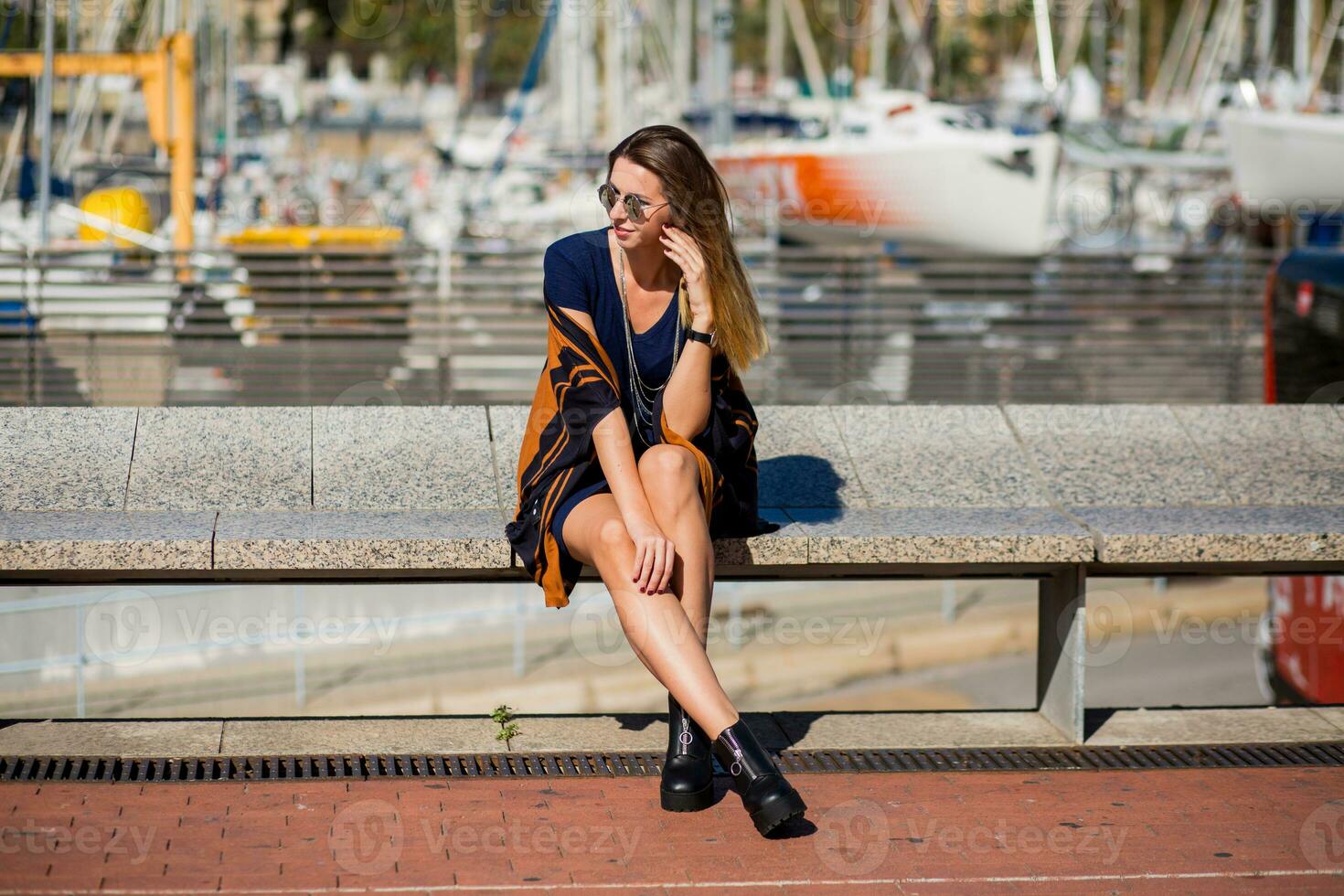 un mujer sentado en un banco en frente de barcos foto