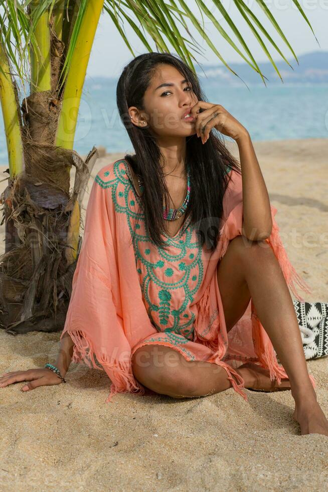 Amazing sexy tan asian woman posing on paradise tropical beach under the pam tree. photo