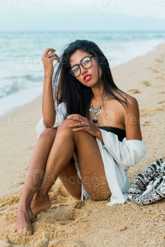 Amazing sensual Asian woman with red lips posing on tropical beach in the evening. photo