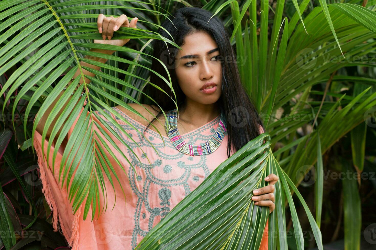 Fashion portrait of  asian woman posing in  garden. Wearing boho dress and accsessorises. photo