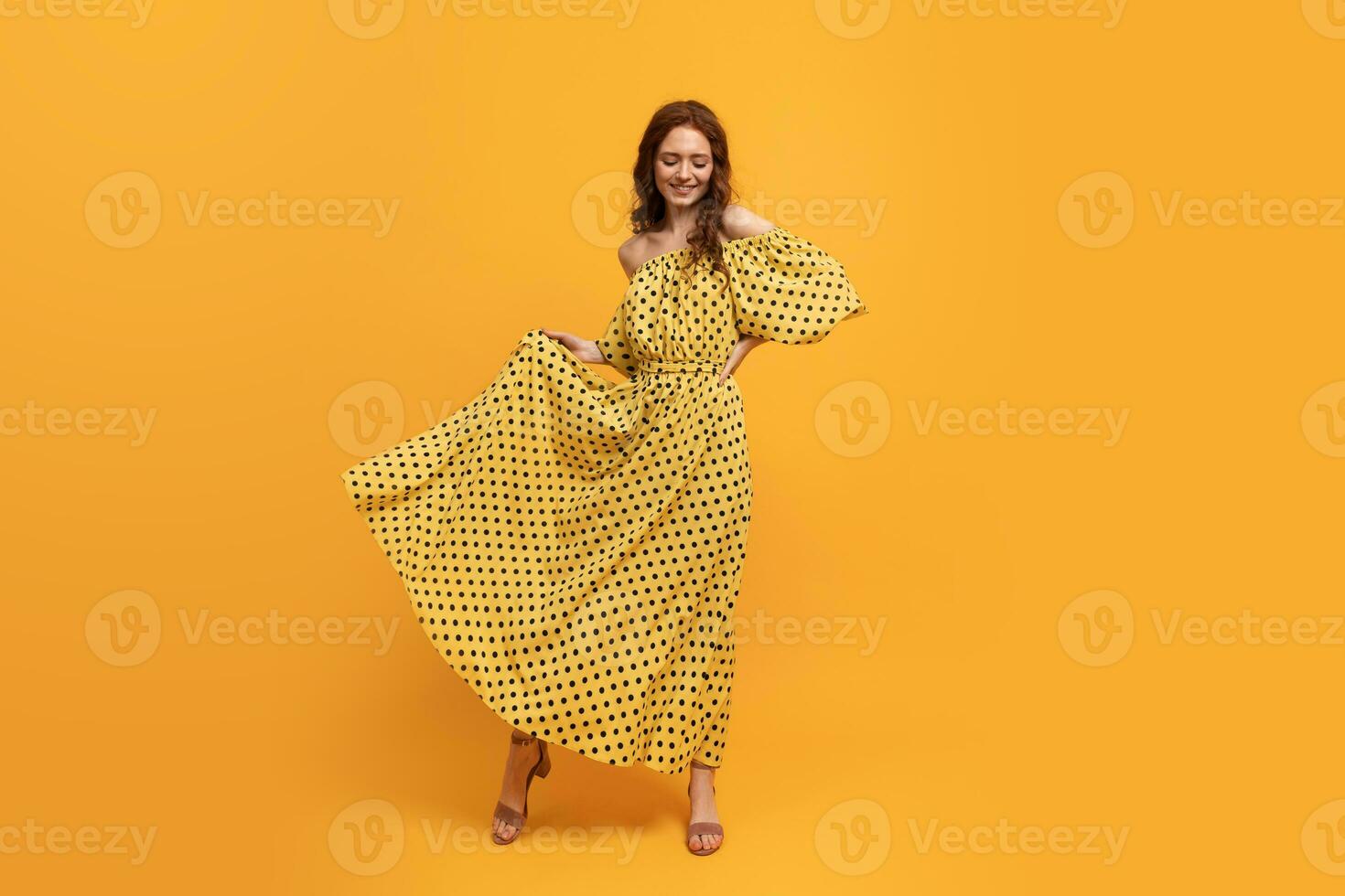 Pretty red-head woman in yellow dress posing in studio. Summer mood. Full lenght. photo