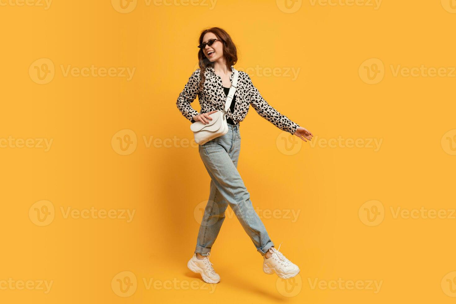 Stylish teen woman in casual outfit and trendy sunglasses posing  on yellow background in studio. Autumn style.  full length photo