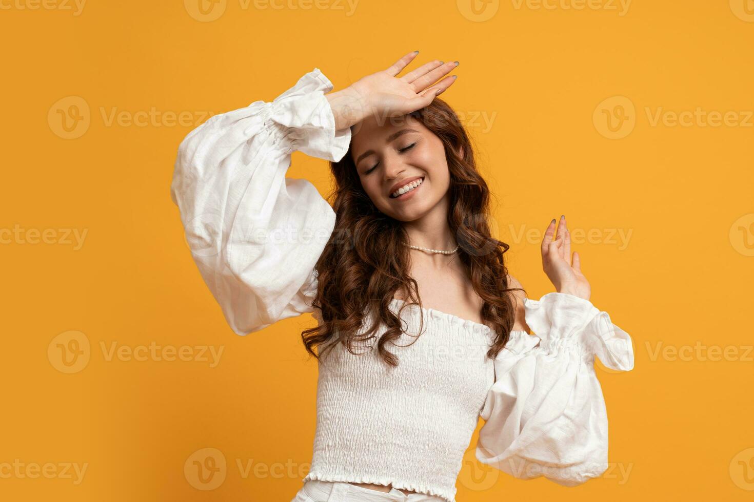 Romantic  elegant woman in white blouse and trousers posing on yellow background in studdio. Summer fashion trends. photo