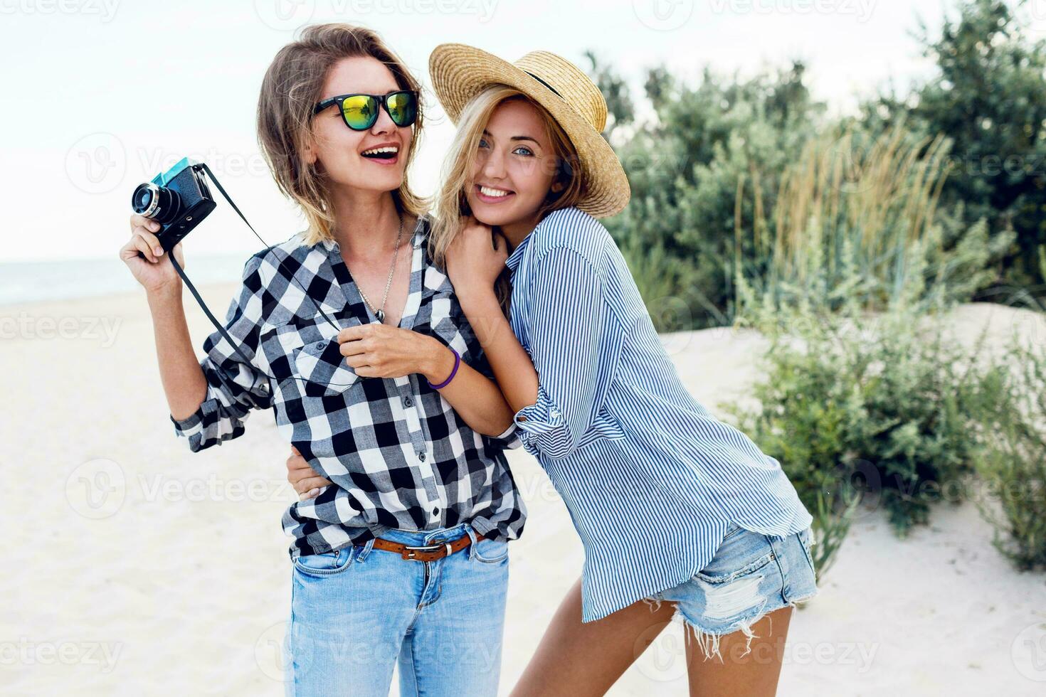 Close up summer lifestyle portrait of two cute women, sisters spending  time together on beach. photo
