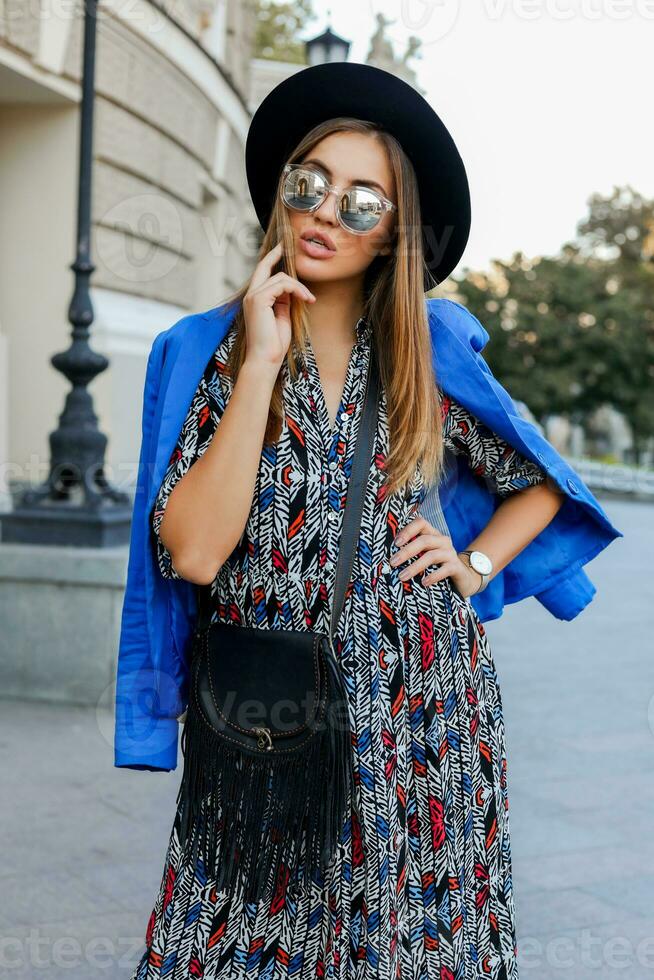 Graceful   girl in elegant  autumn outfit walking while holidays in Europe. Stylish leather bag.  Blue jacket and black hat. photo