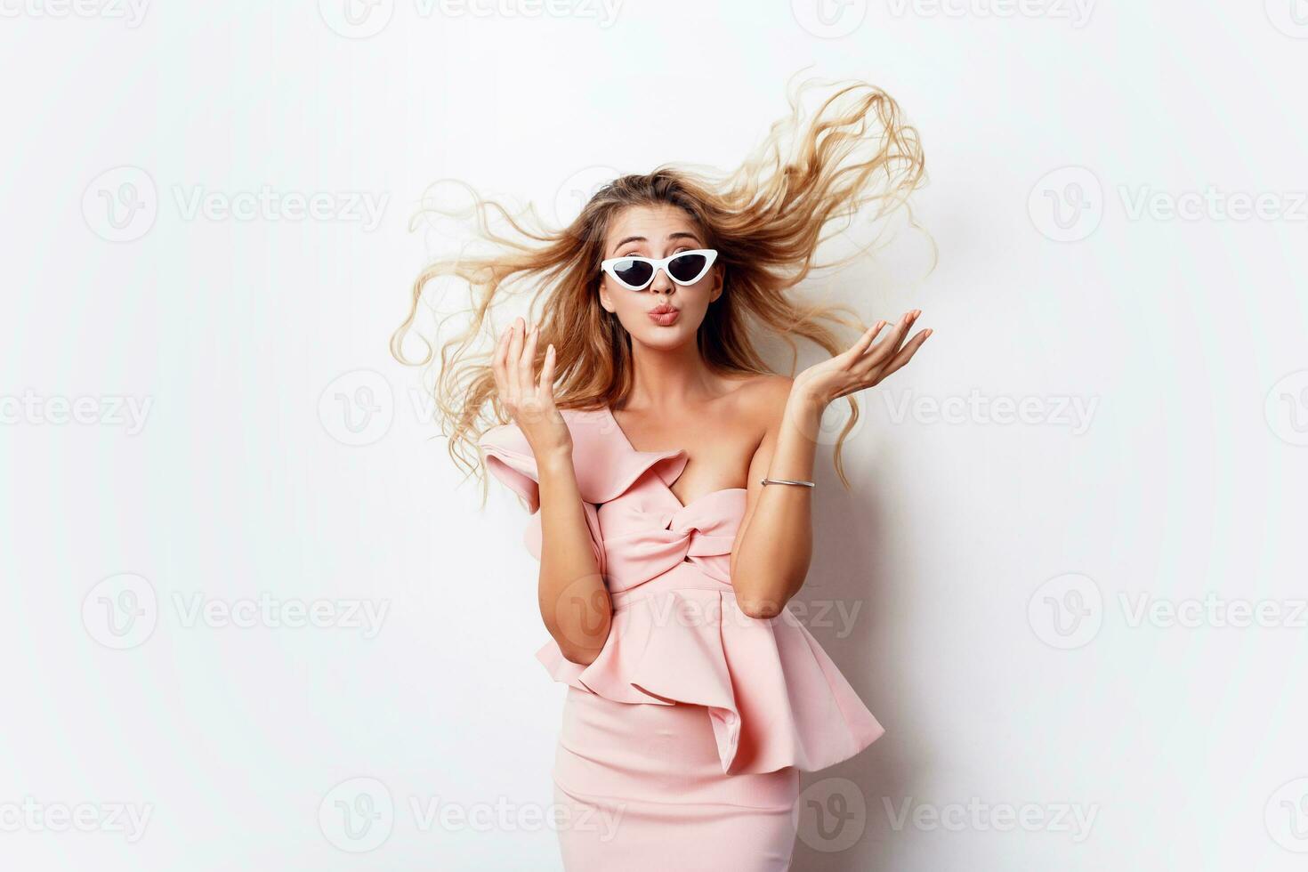 . Amazed     Emotions. Surprised face. Blonde woman in party pink dress posing on white background. Stylish sunglasses. photo