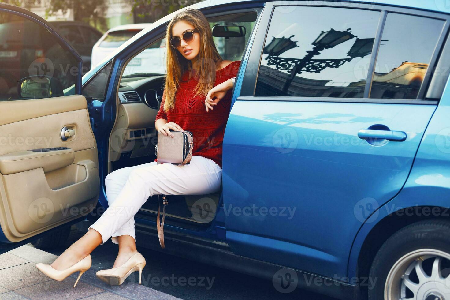 Pretty  sexy stylish  woman in car. Successful young lady  posing on street , sitting in her vehicle. Wearing stylish  fall outfit, sunglasses, white  trousers and elegant handbag. photo