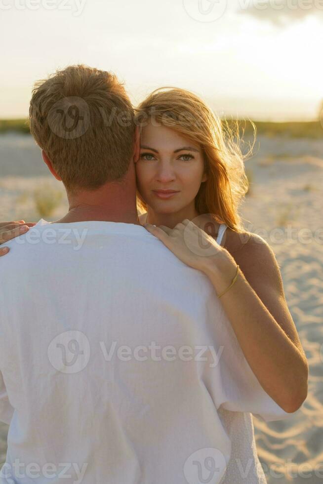 Outdoor summer  image of young beautiful stylish couple on the beach. Warm soft toned image. Sunset background. Romantic mood. photo