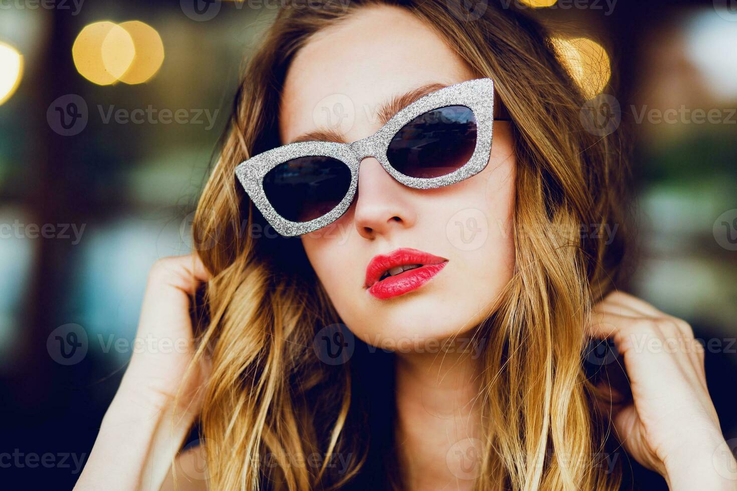 Close up fashion portrait of glamour stylish  blonde  lady   with cool retro sunglasses . The girl sitting in cafe and enjoying  time out. photo