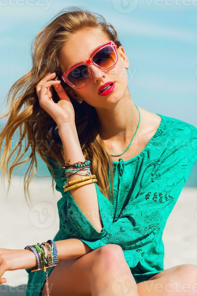 Stunning colorful outdoor summer portrait of pretty young blonde beautiful woman in  cool sunglasses posing on the sunny tropical  beach. photo