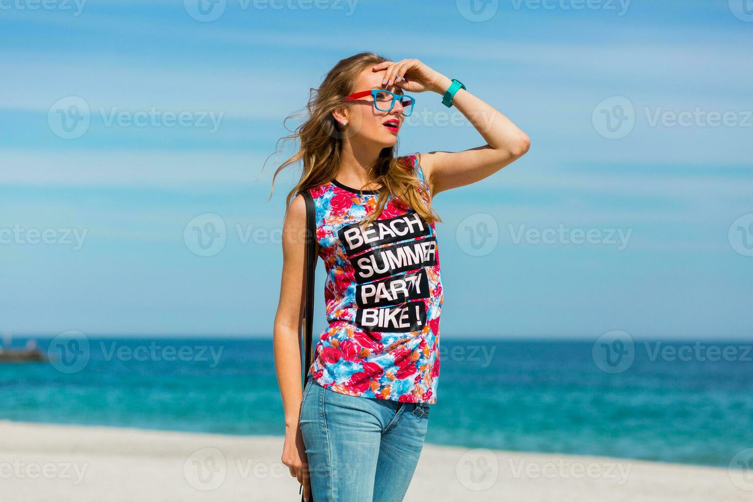 Outdoor fashion lifestyle summer vacation  portrait of pretty young  sensual stunning woman with  blond hairs  and sunglasses  posing on the paradise  tropical beach. photo