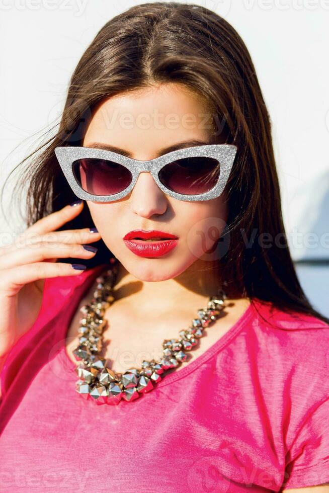 de moda mujer en verano ropa y Gafas de sol posando terminado blanco urbano antecedentes. foto