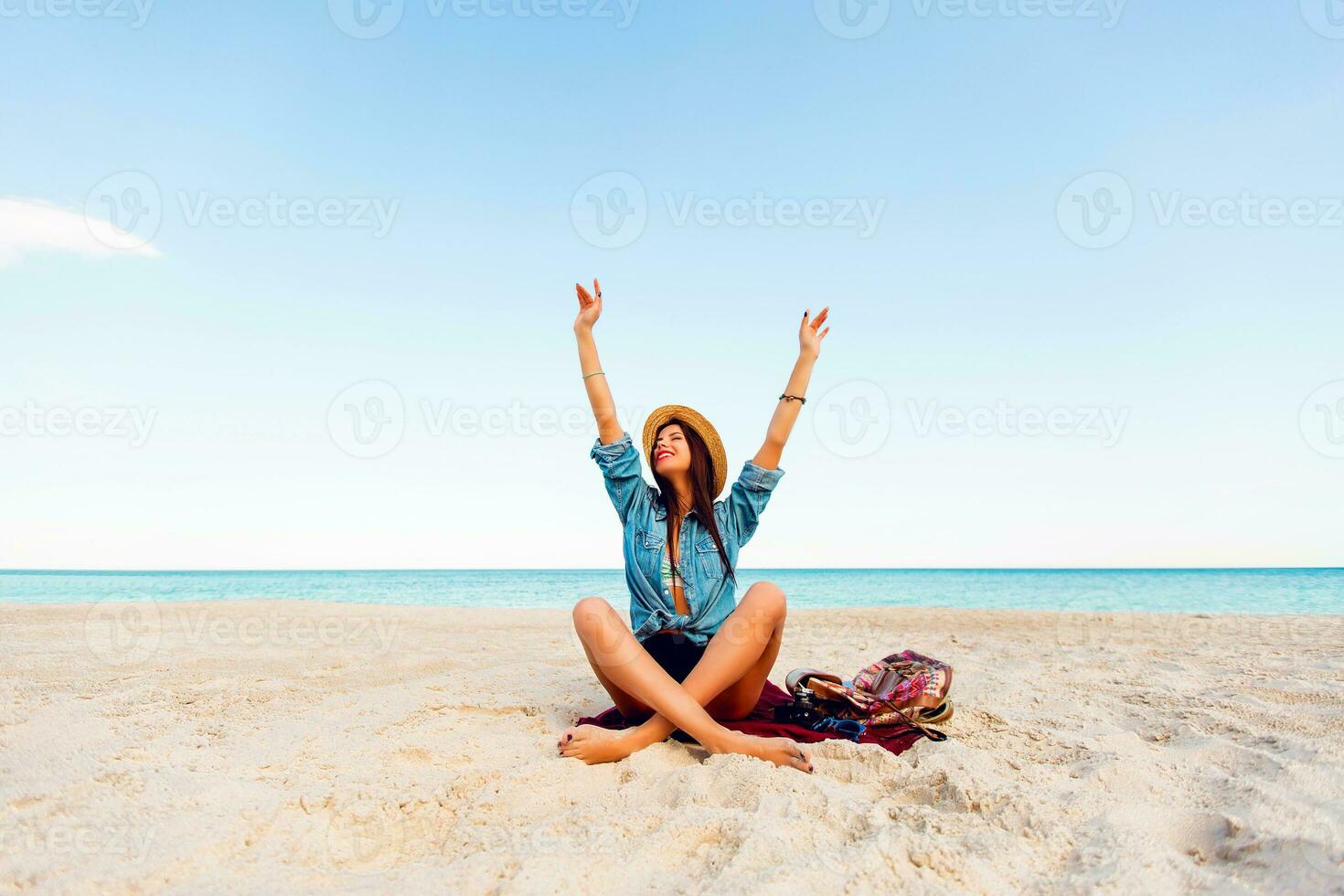 maravilloso sexy mujer con Perfecto bronceado cuerpo, lleno rojo labios y l largo piernas posando en el tropical soleado playa. vistiendo cosecha parte superior , pantalones cortos y Paja sombrero. brillante soleado colores. foto