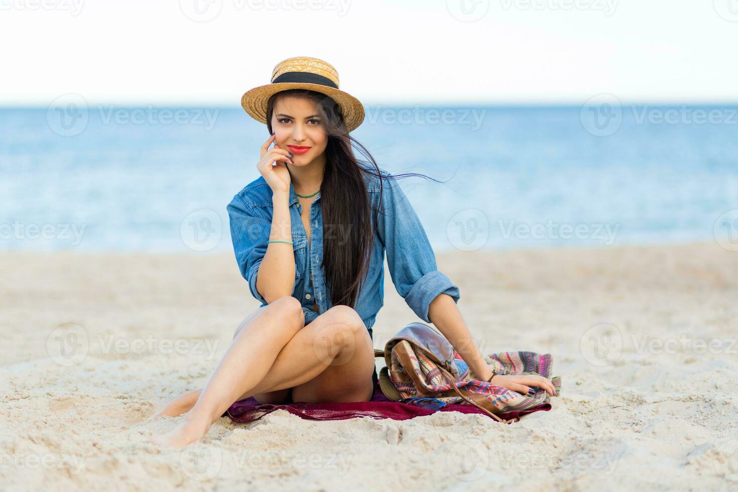 Gorgeous sexy woman with perfect tan body, full red lips and l  long legs posing on the  tropical  sunny beach. Wearing  crop top , shorts and straw hat. Bright sunny colors. photo