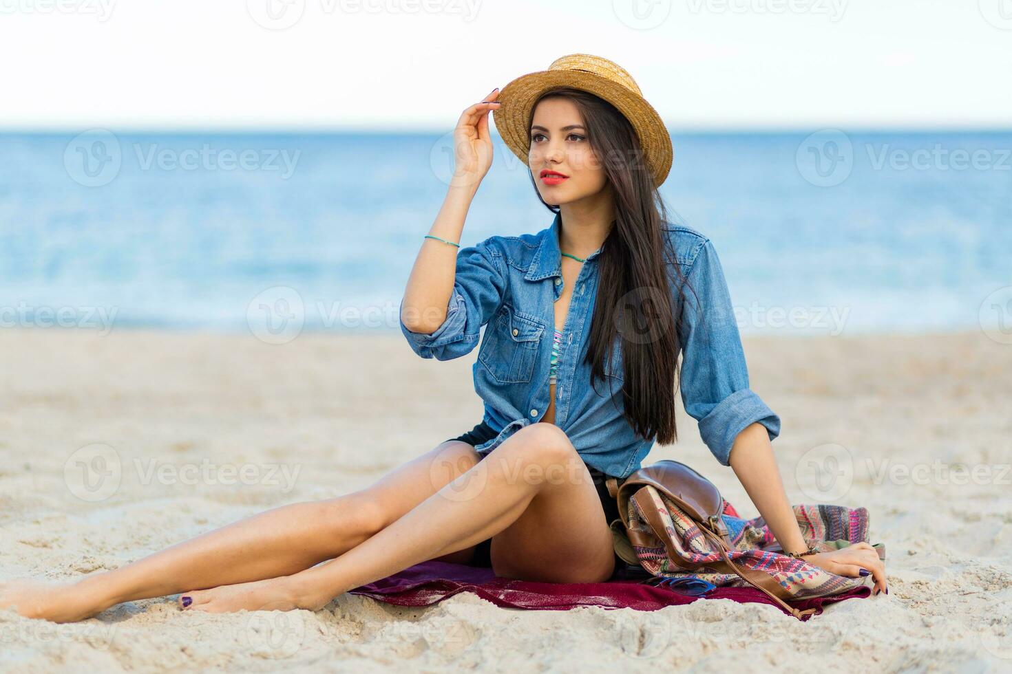 maravilloso sexy mujer con Perfecto bronceado cuerpo, lleno rojo labios y l largo piernas posando en el tropical soleado playa. vistiendo cosecha parte superior , pantalones cortos y Paja sombrero. brillante soleado colores. foto