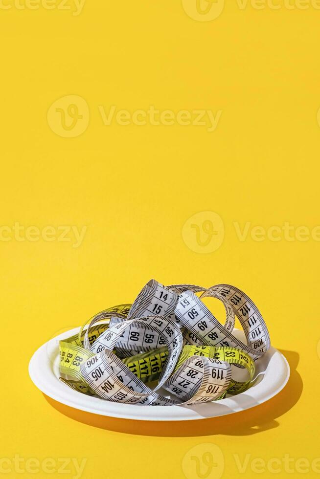 colorful measuring tapes top view on disposable plate on bright yellow background photo