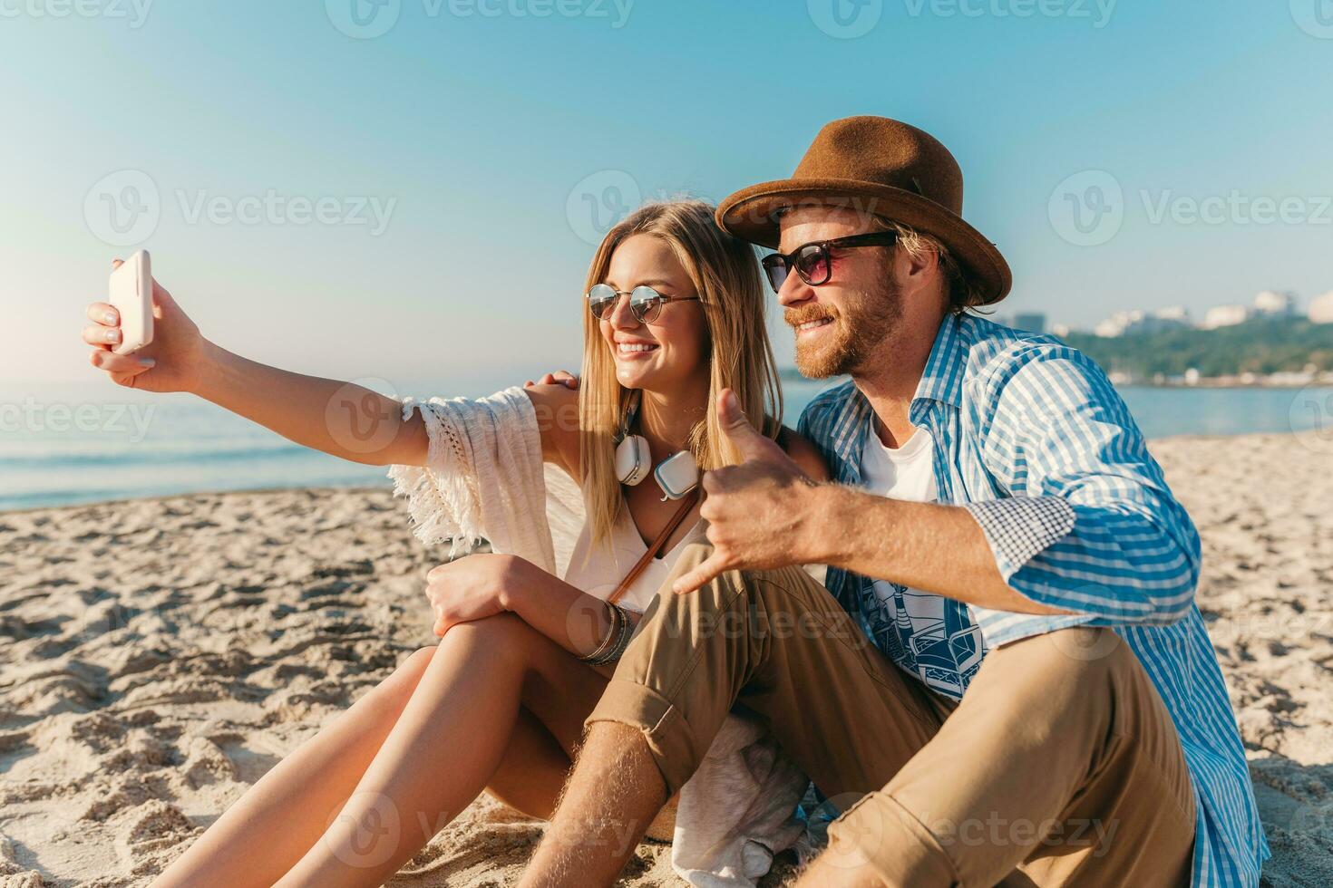 young attractive smiling happy man and woman in sunglasses lying on sand beach photo