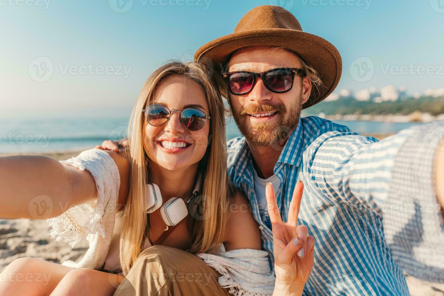 young attractive smiling happy man and woman in sunglasses lying on sand beach photo