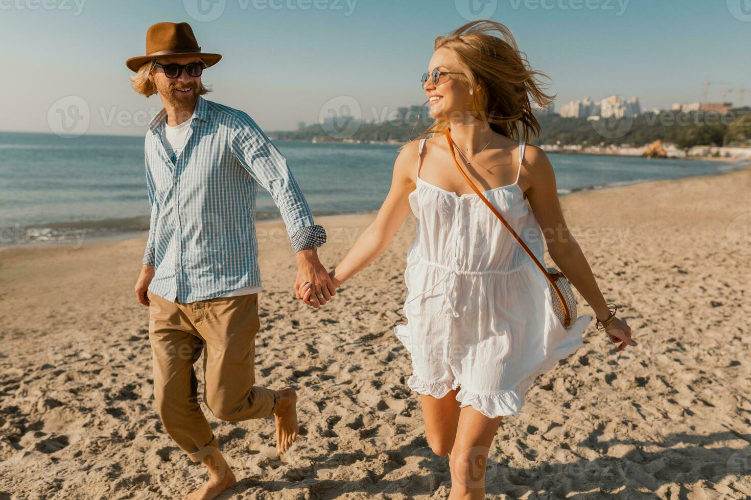 young attractive smiling happy man and woman running together on beach photo