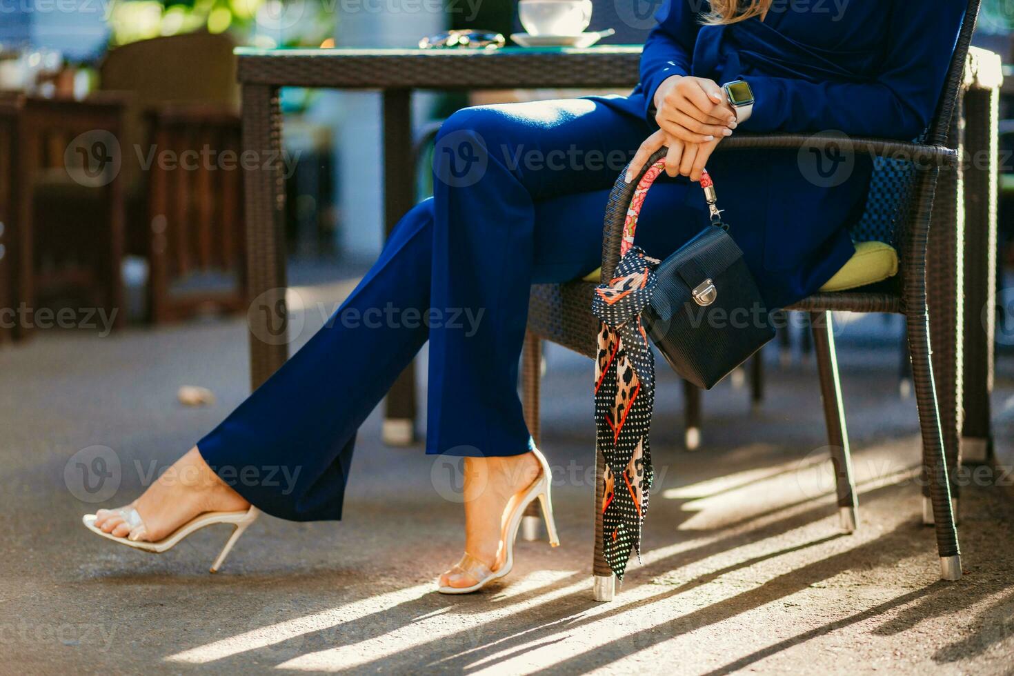 attractive woman dressed in blue elegant suit sitting in cafe in city street photo