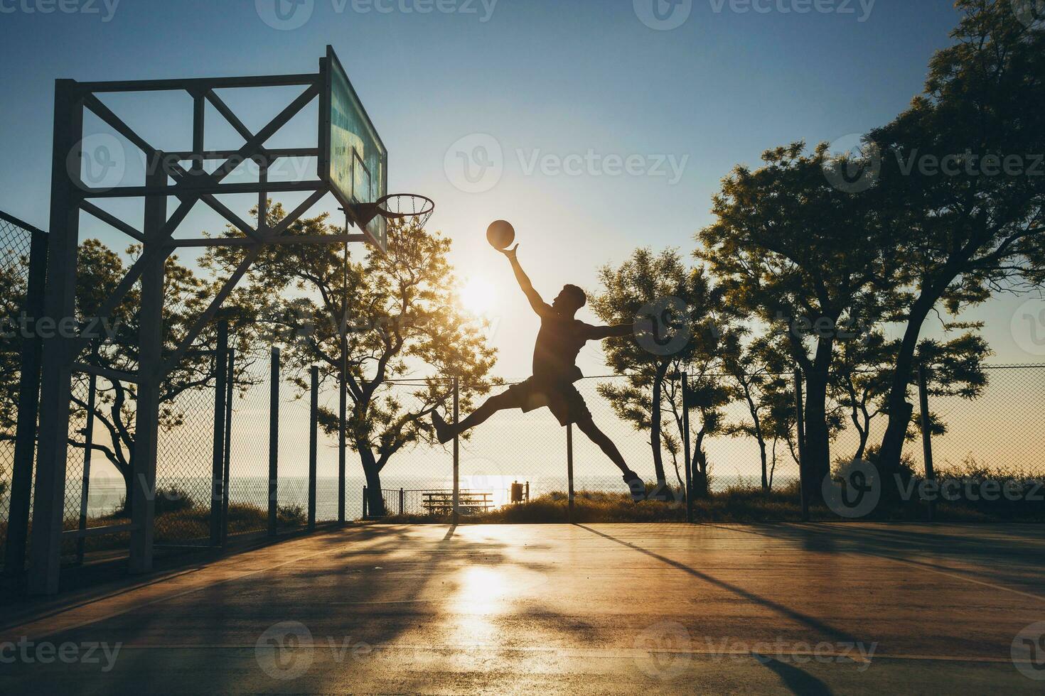 black man doing sports, playing basketball on sunrise, jumping silhouette photo