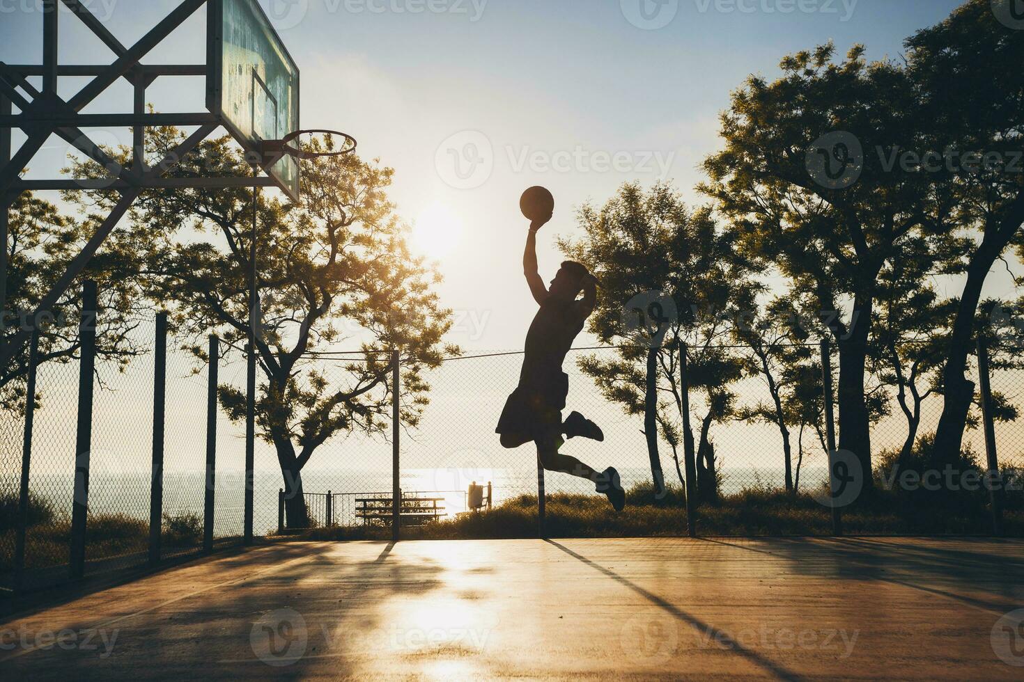 black man doing sports, playing basketball on sunrise, jumping silhouette photo