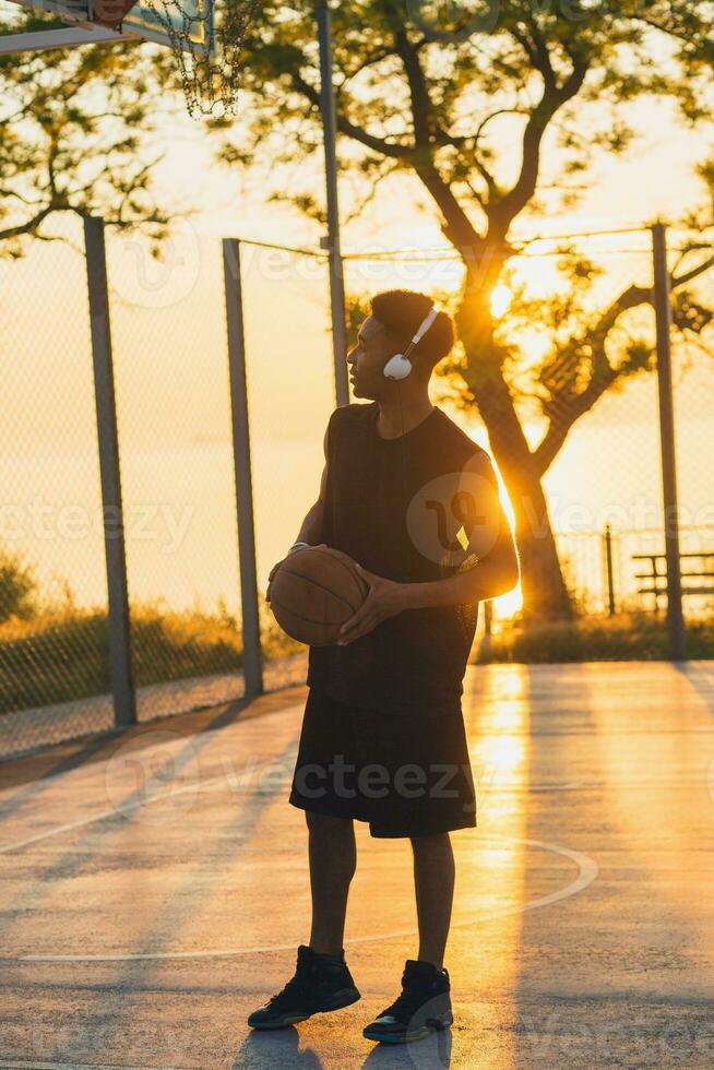 black man doing sports, playing basketball on sunrise, active lifestyle, sunny summer morning photo