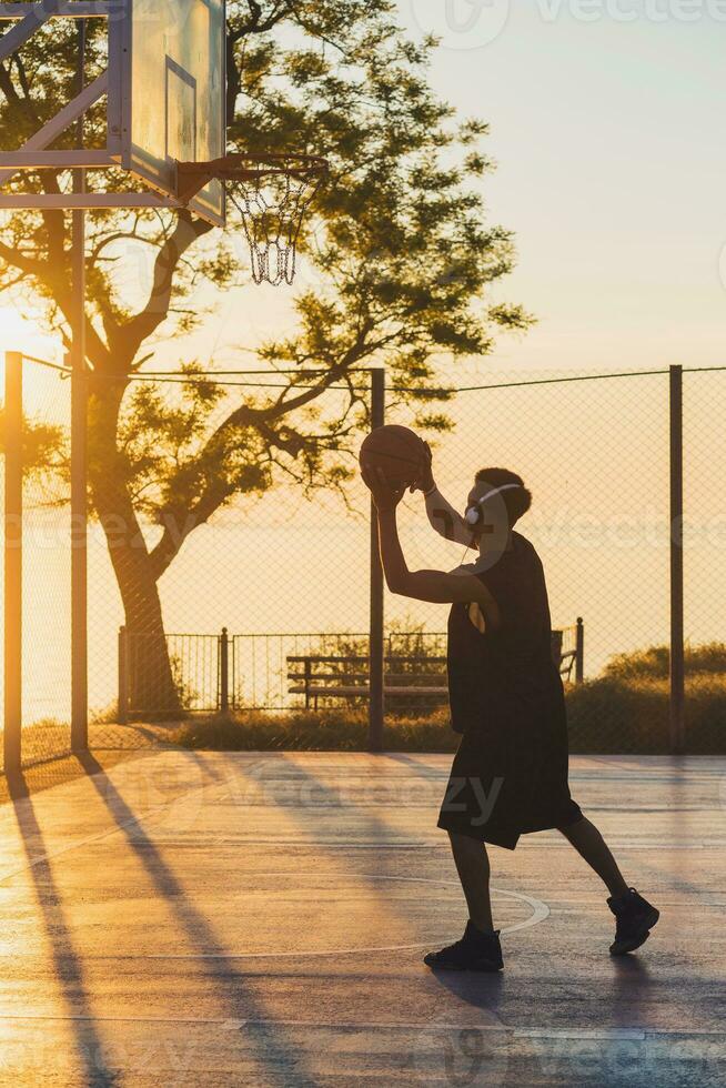 black man doing sports, playing basketball on sunrise, active lifestyle, sunny summer morning photo