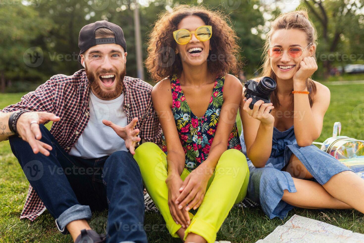 happy young company of talking smiling friends sitting park photo