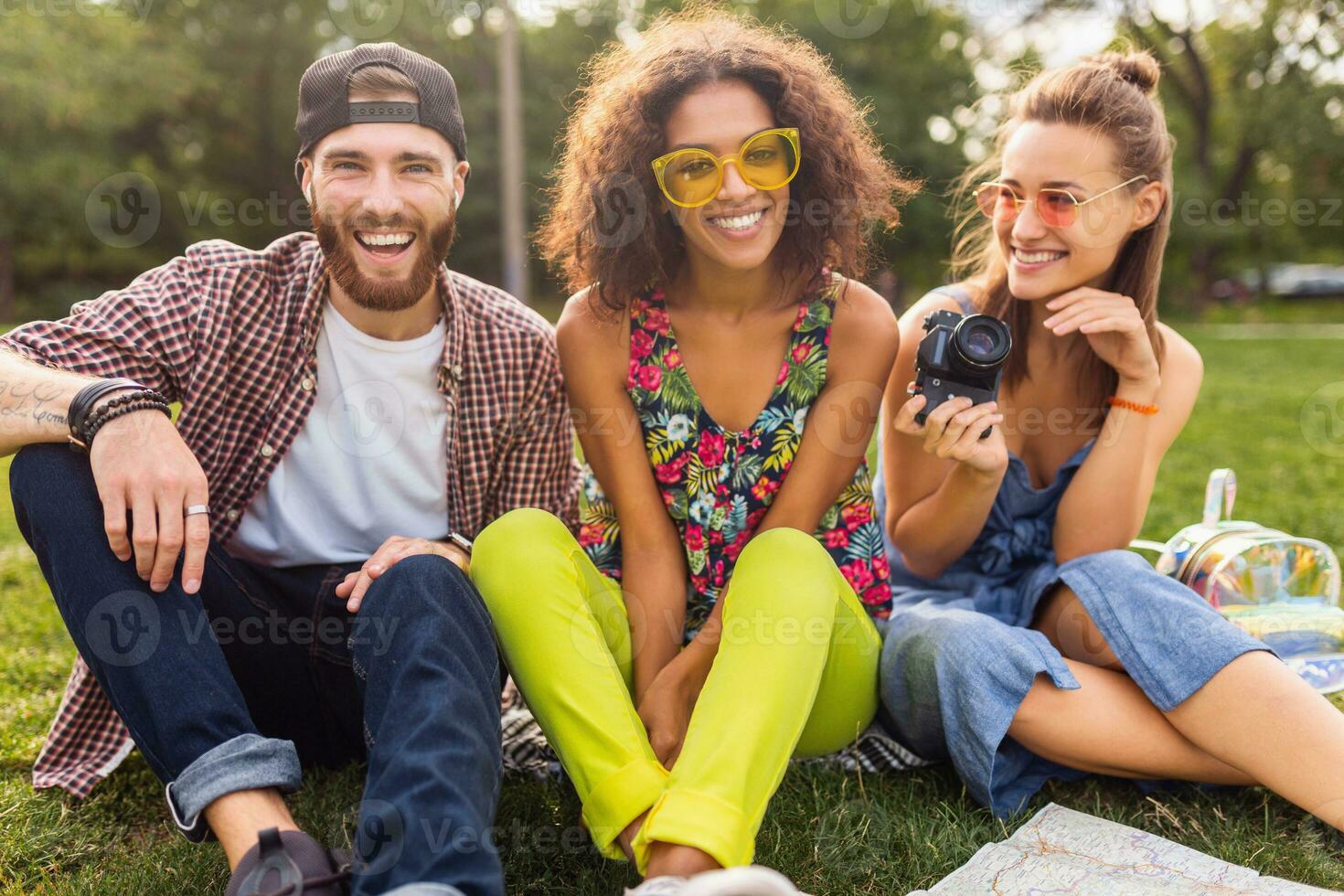 happy young company of talking smiling friends sitting park photo