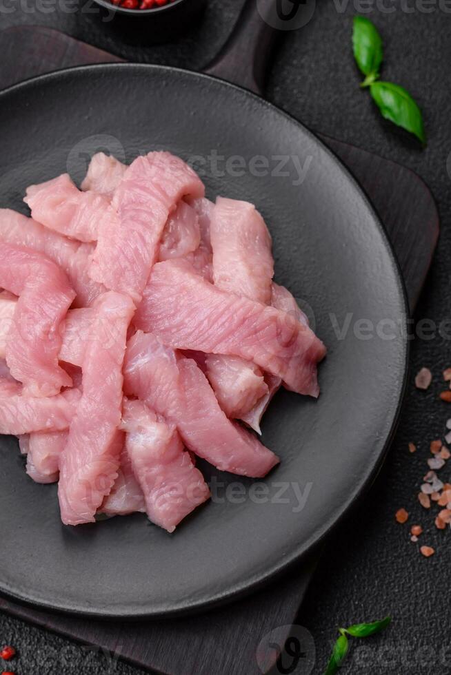 Raw turkey meat in the form of slices with salt, spices and herbs photo