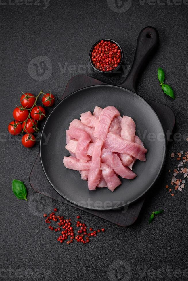 Raw turkey meat in the form of slices with salt, spices and herbs photo