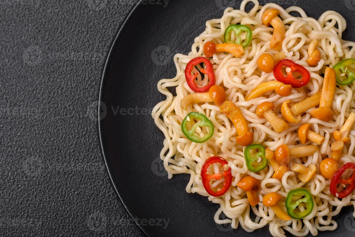 Delicious Asian cuisine dish with rice noodles, peppers, mushrooms and spices photo