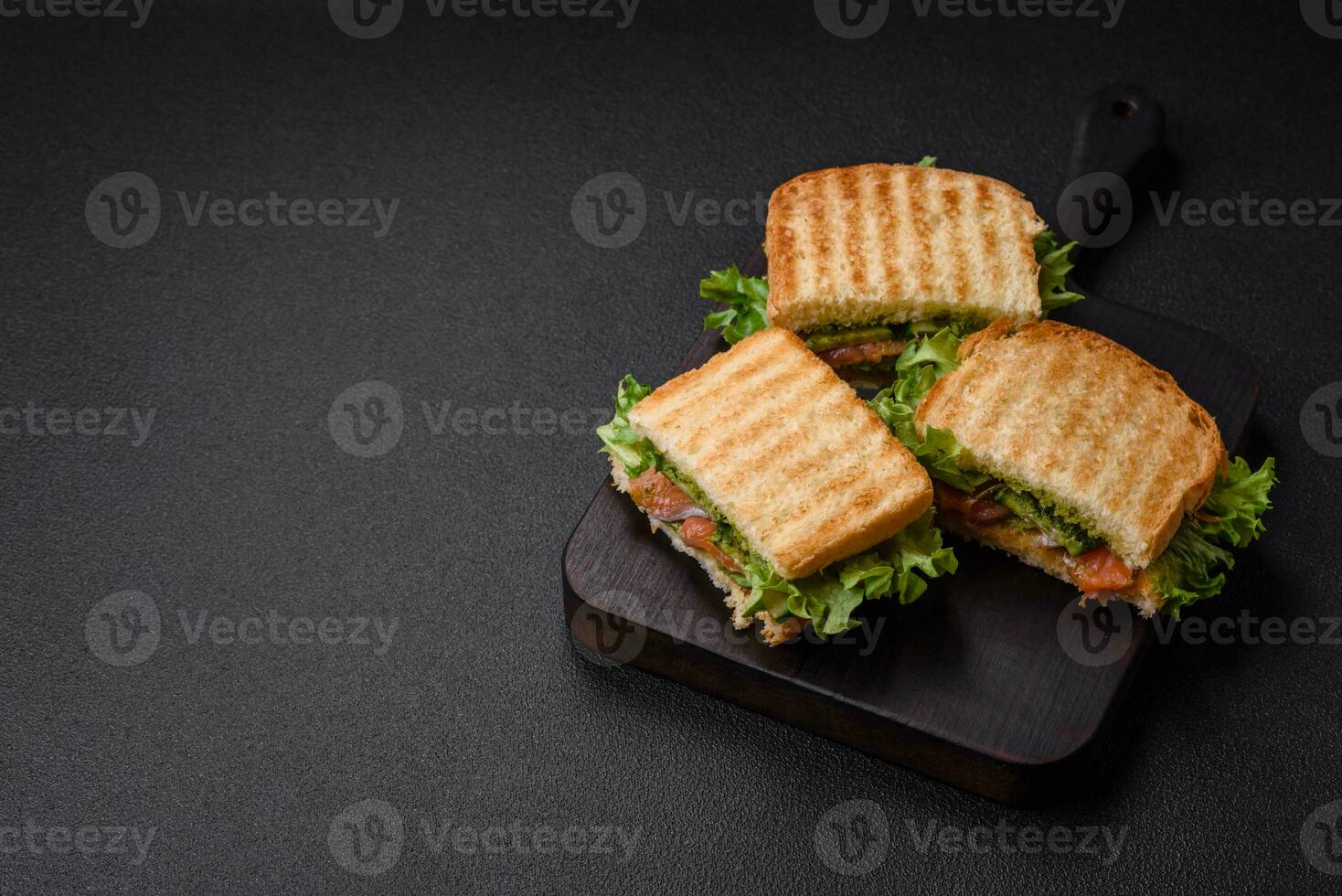 Delicious crispy sandwich with toast, salmon, avocado, tomatoes, salt, spices and herbs photo