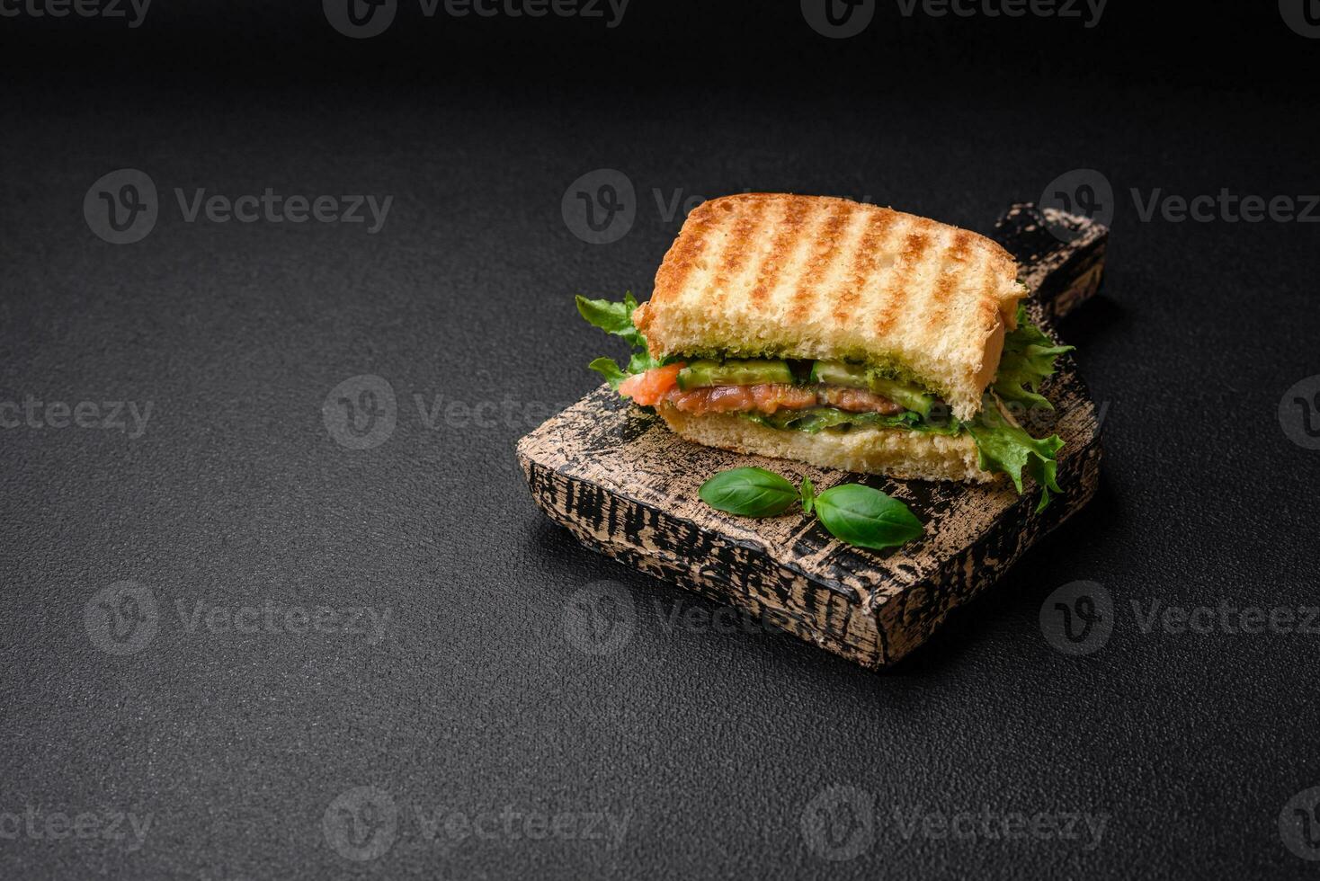 Delicious crispy sandwich with toast, salmon, avocado, tomatoes, salt, spices and herbs photo