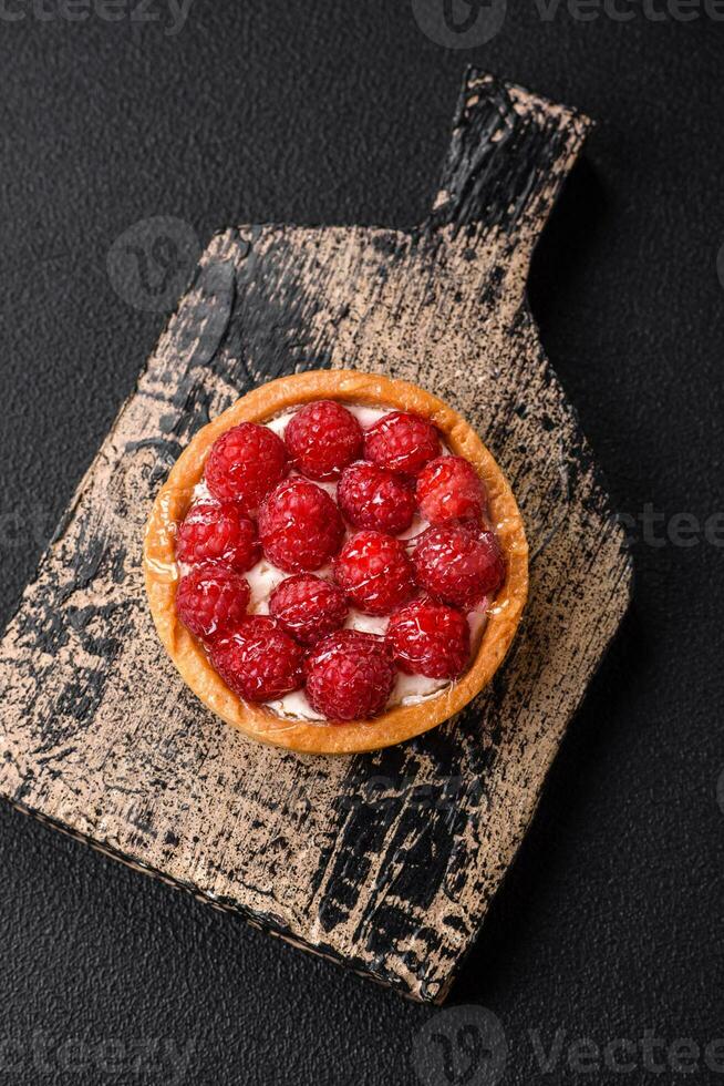 Delicious fresh sweet round tart with ripe raspberries and cream photo