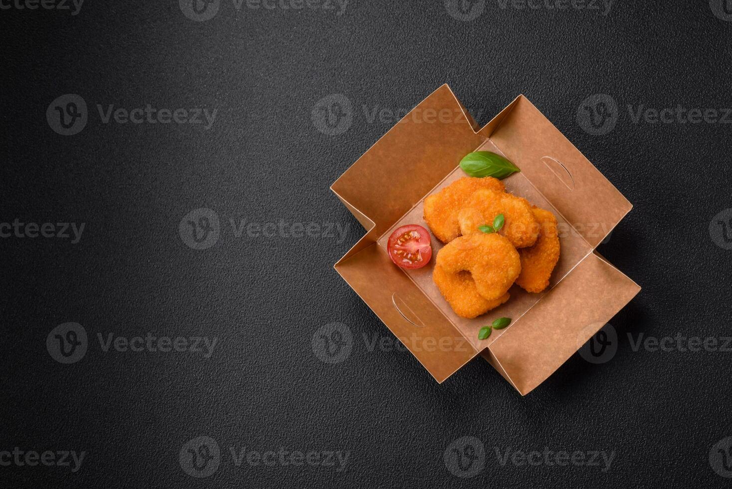 Delicious fresh crispy chicken nuggets on a dark concrete background photo