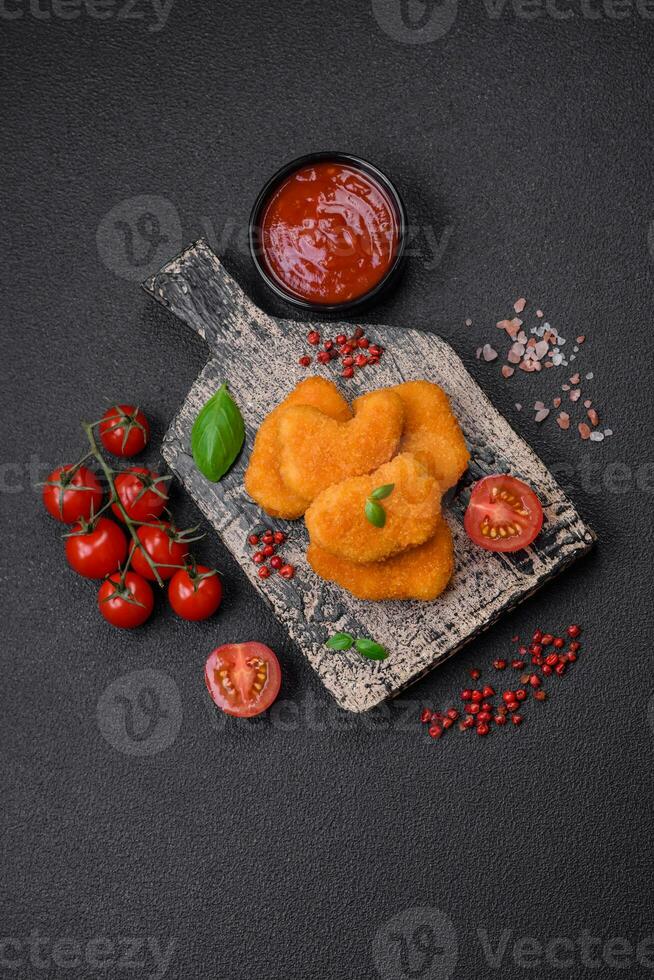 Delicious fresh crispy chicken nuggets on a dark concrete background photo