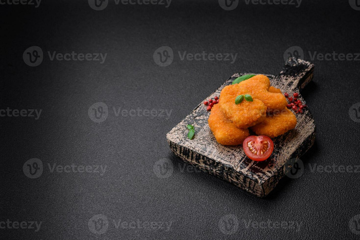 Delicious fresh crispy chicken nuggets on a dark concrete background photo